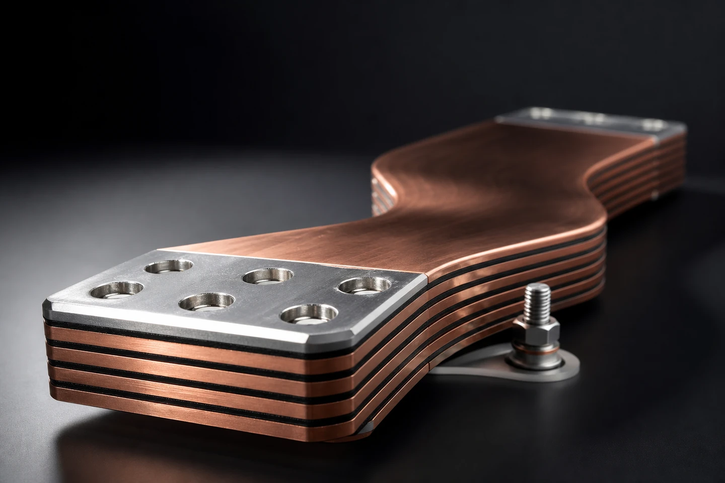 Polished laminated copper busbar with silver-plated contact ends on charcoal backdrop